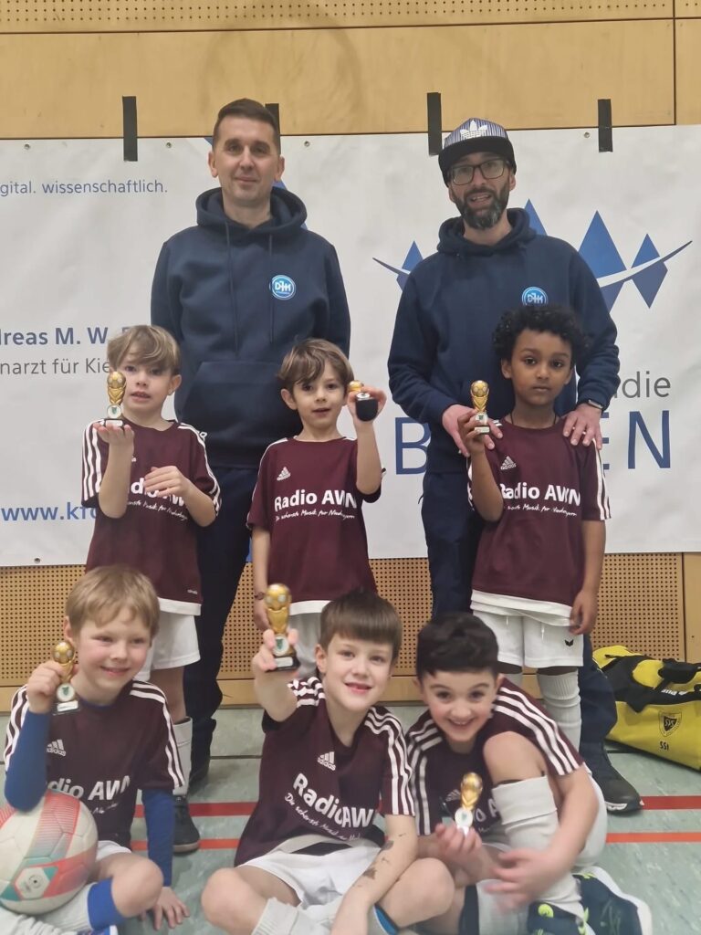 Spieler und Trainer der DJK Straubing G-Jugend präsentieren stolz ihre Pokale nach dem Turnier
