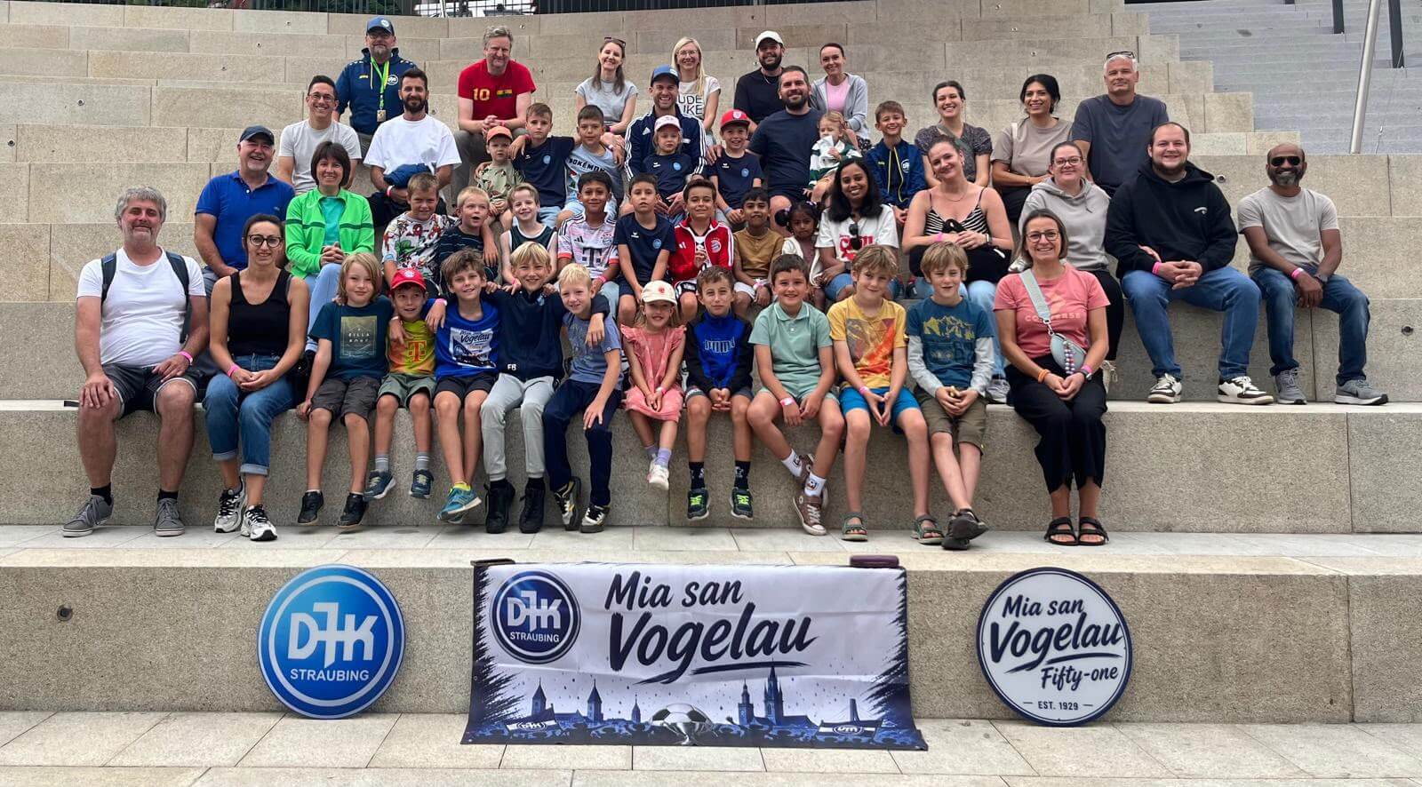 Gruppenfoto der E2/F-Jugend der DJK SB Straubing mit Trainern, Eltern und Geschwistern beim Mannschaftsausflug in den Edelwies Freizeitpark 2026 vor dem Mia-san-Vogelau-Banner.