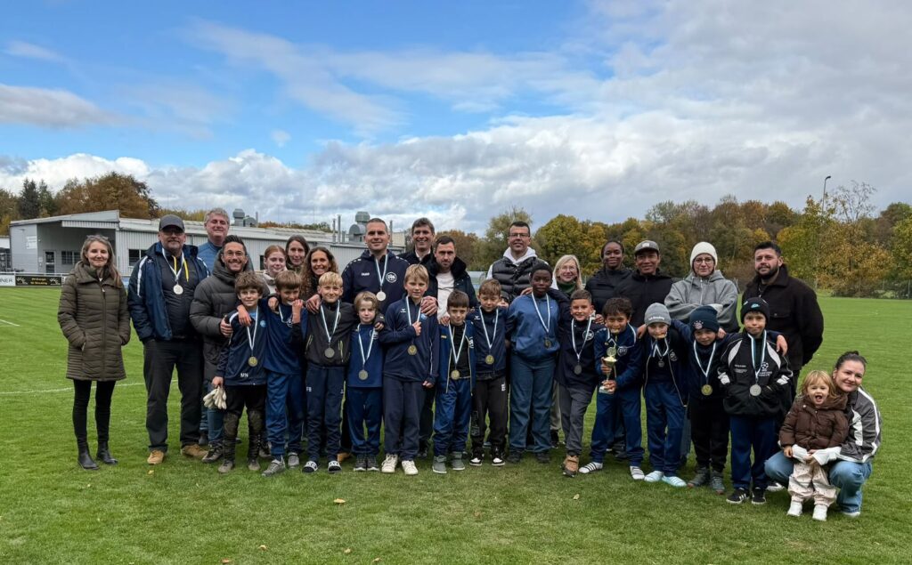 DJK SB Straubing E1-Jugend mit Medaillen, Trainer und Eltern auf dem Rasen nach dem Abschluss der Herbstrunde 2026 auf Platz 3