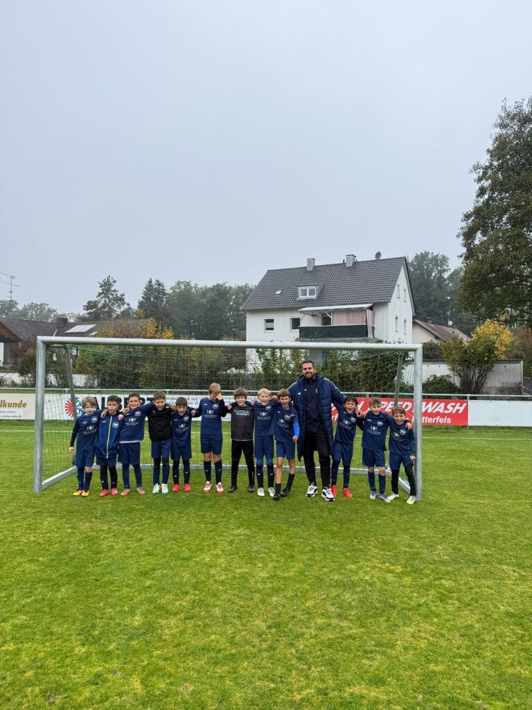 Mannschaftsfoto der DJK SB Straubing E1-Jugend mit Trainer vor dem Tor nach dem 5:1-Auswärtssieg beim SC 1928 Rain im Oktober 2026